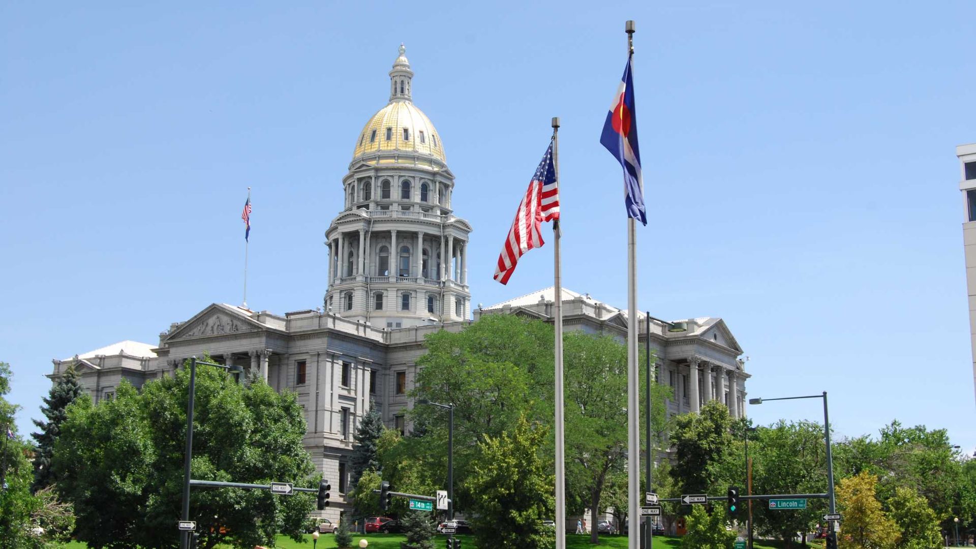 Three flags are flying in front of a large building