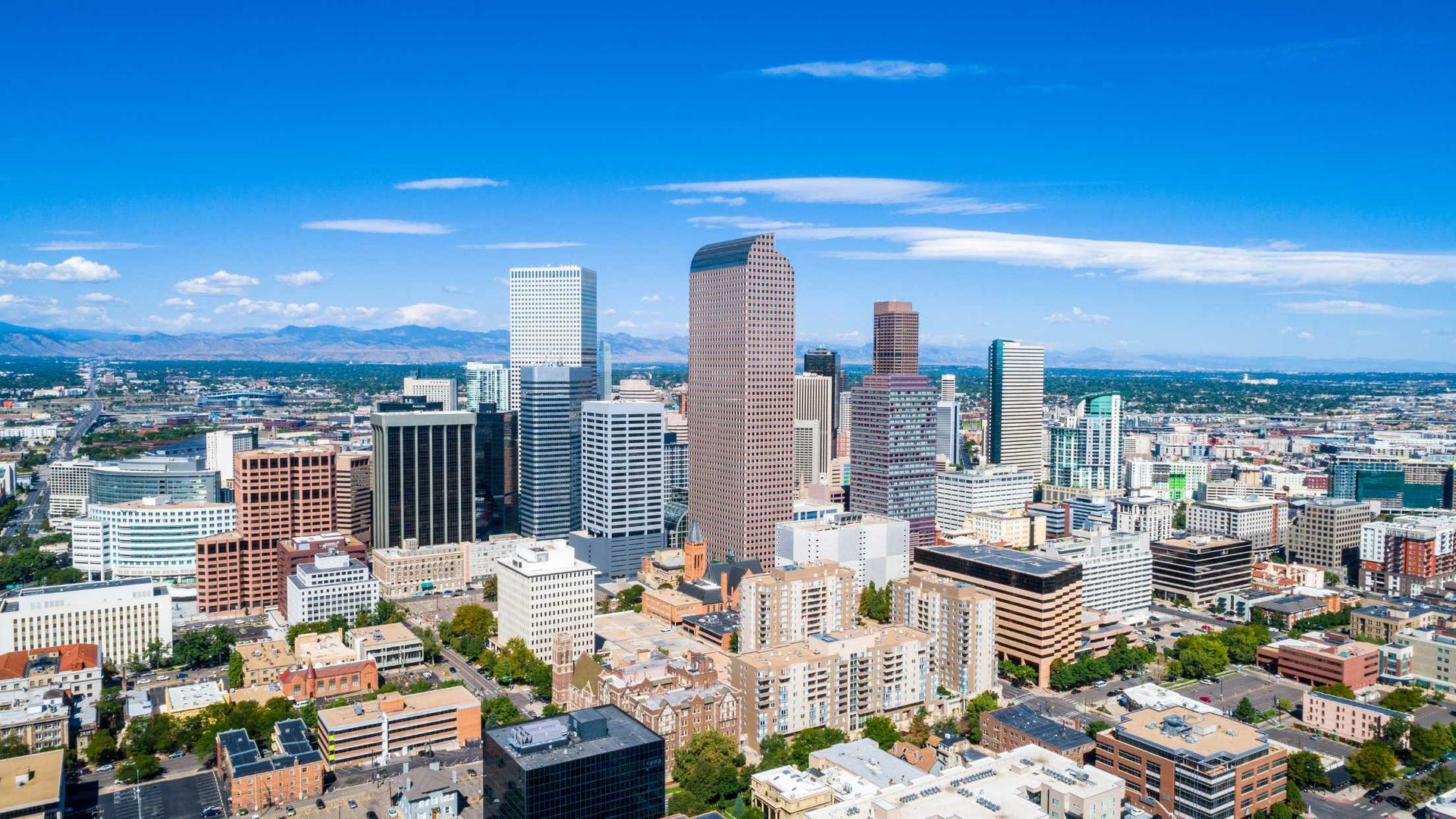 An aerial view of a city skyline with mountains in the background.