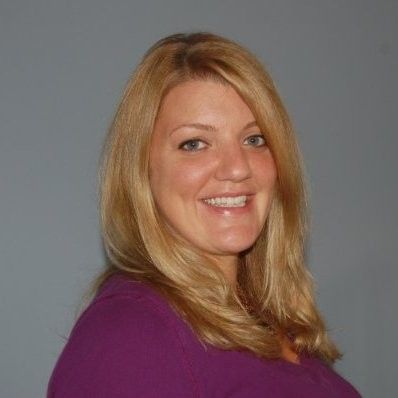 A woman in a purple shirt is smiling for the camera.