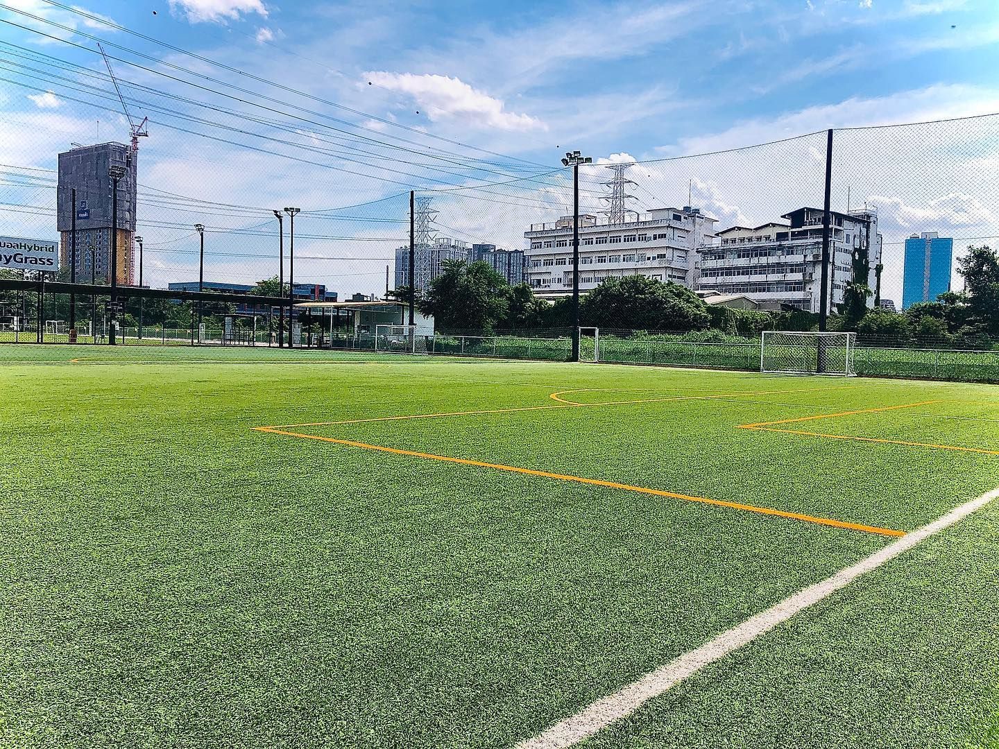 A soccer field with a fence and a city in the background.