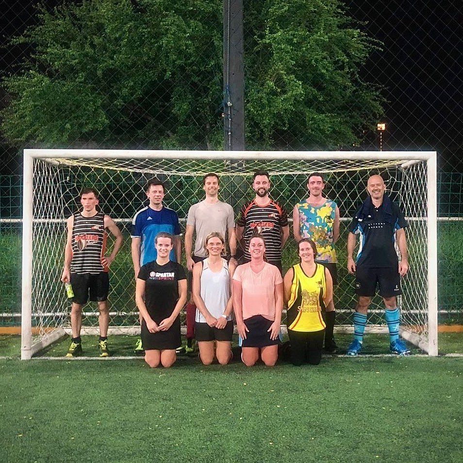 A group of people are posing for a picture in front of a soccer goal.