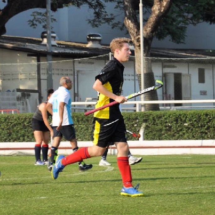 A man holding a hockey stick is running on a field