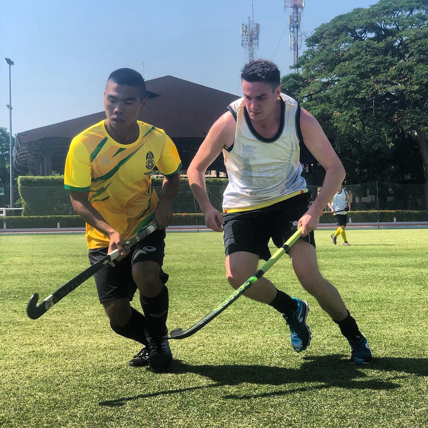 Two men are playing a game of field hockey on a field