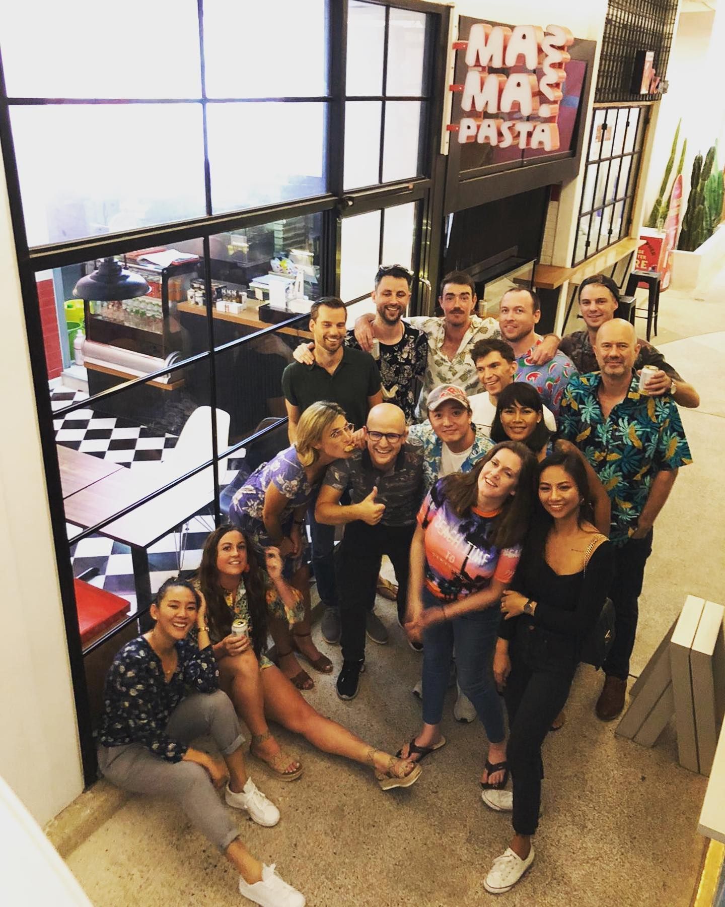 A group of people posing for a picture in front of a sign that says mas mas pasta