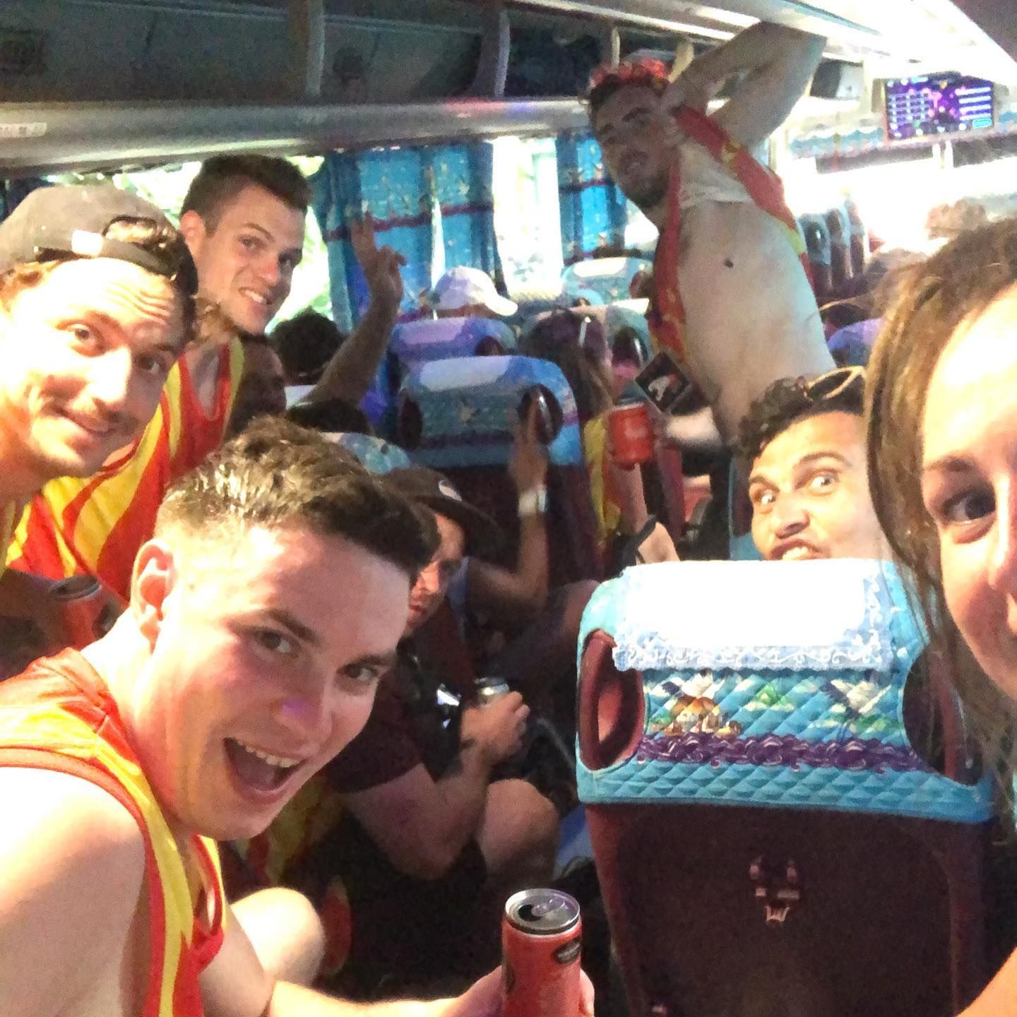 A group of people are sitting on a bus and one of them is holding a can of soda