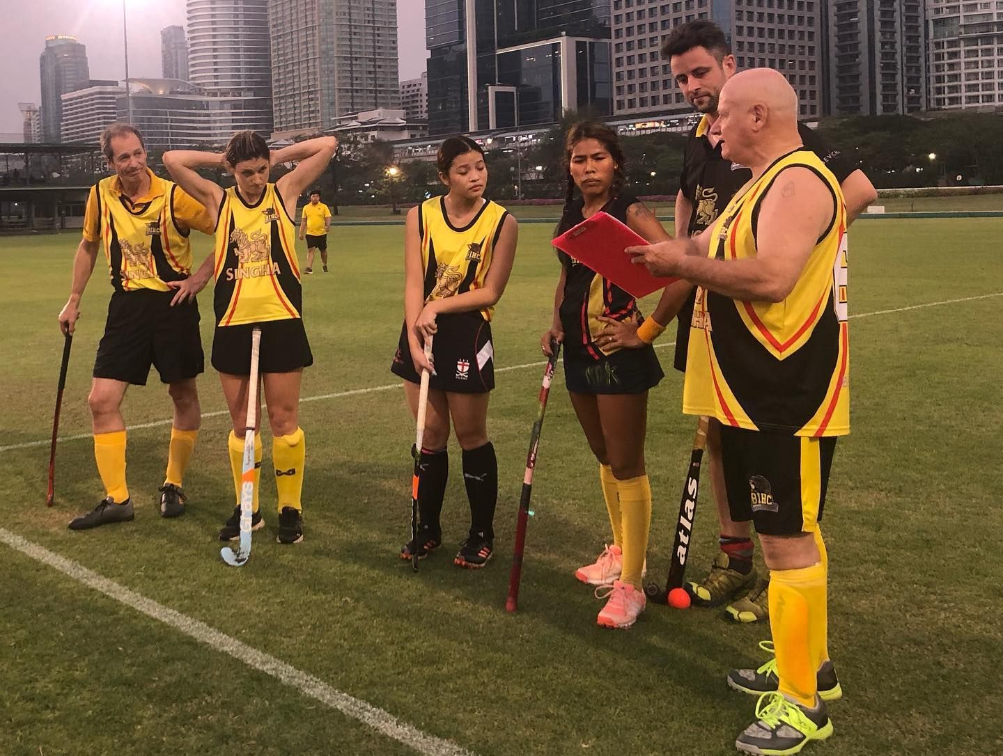 A group of people are standing on a field holding hockey sticks.