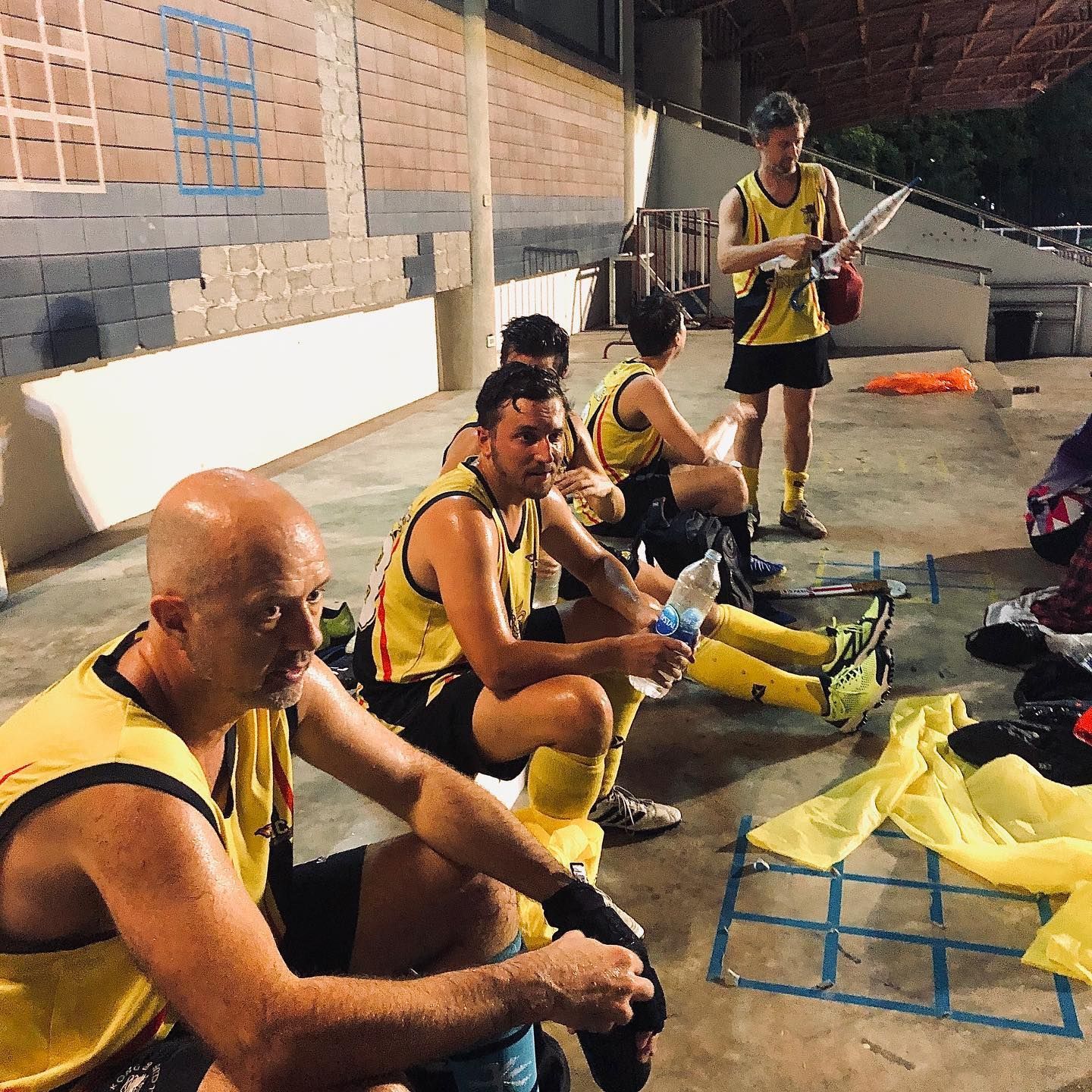 A group of men in yellow jerseys are sitting on the ground