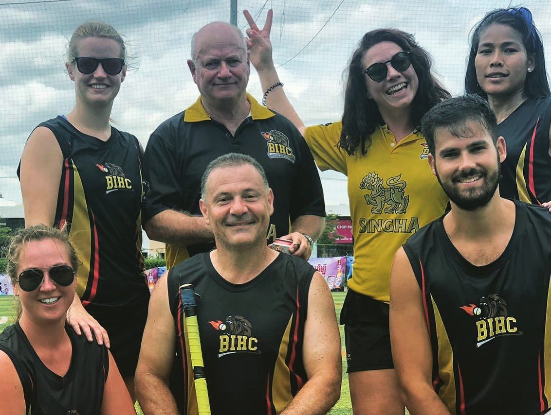 Group of people in black and yellow athletic gear, smiling outside; a man is holding up a peace sign.
