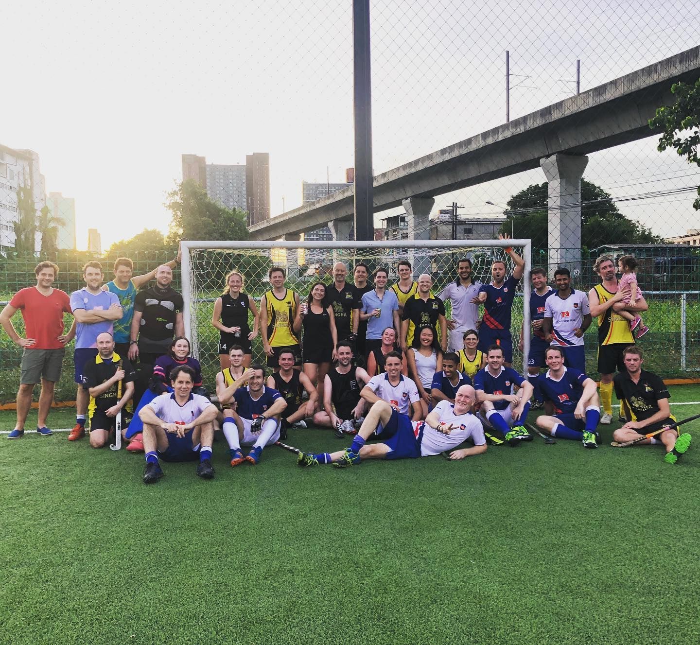 A group of people are posing for a picture on a soccer field.