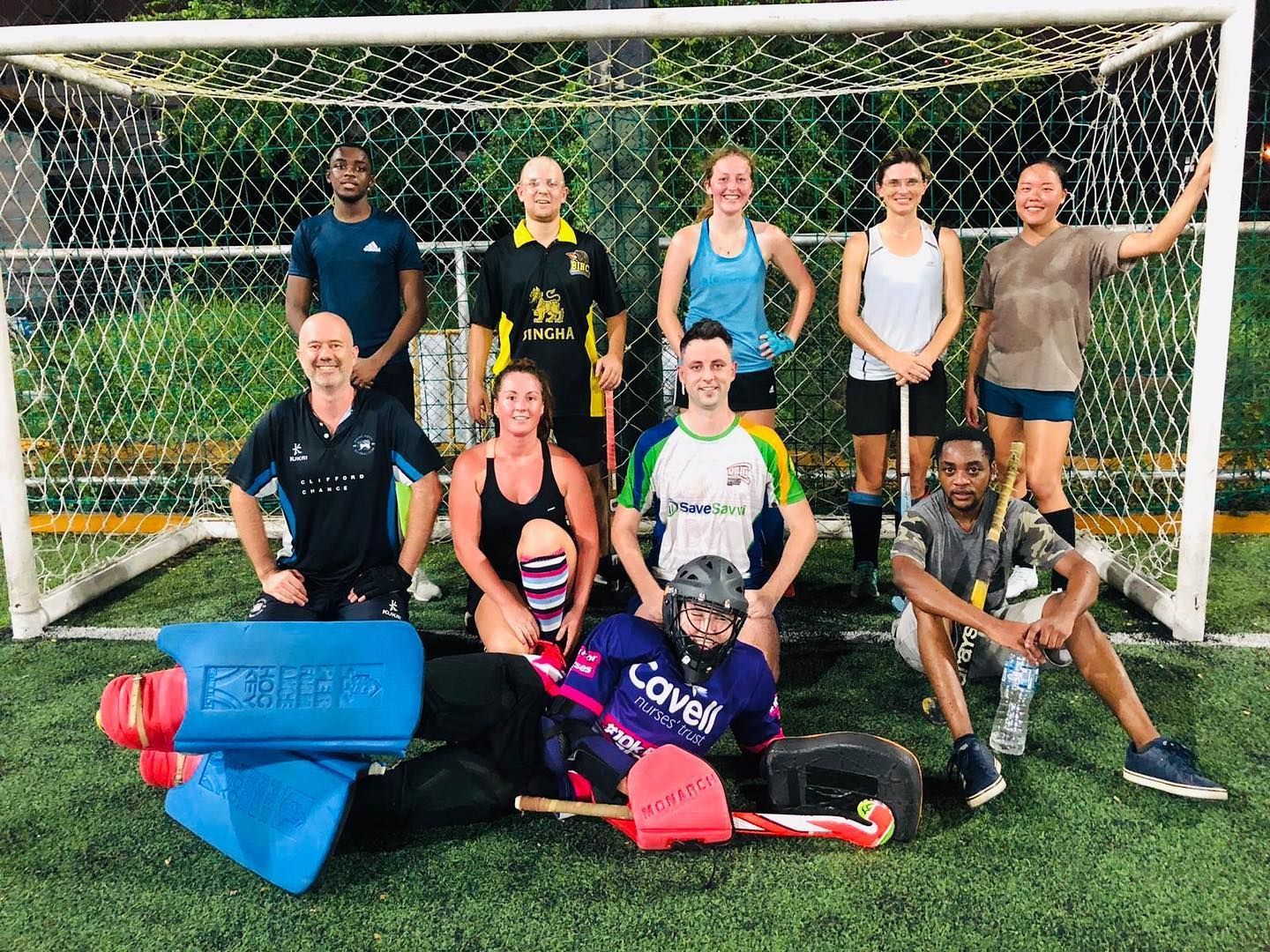 A group of people are posing for a picture in front of a soccer goal.
