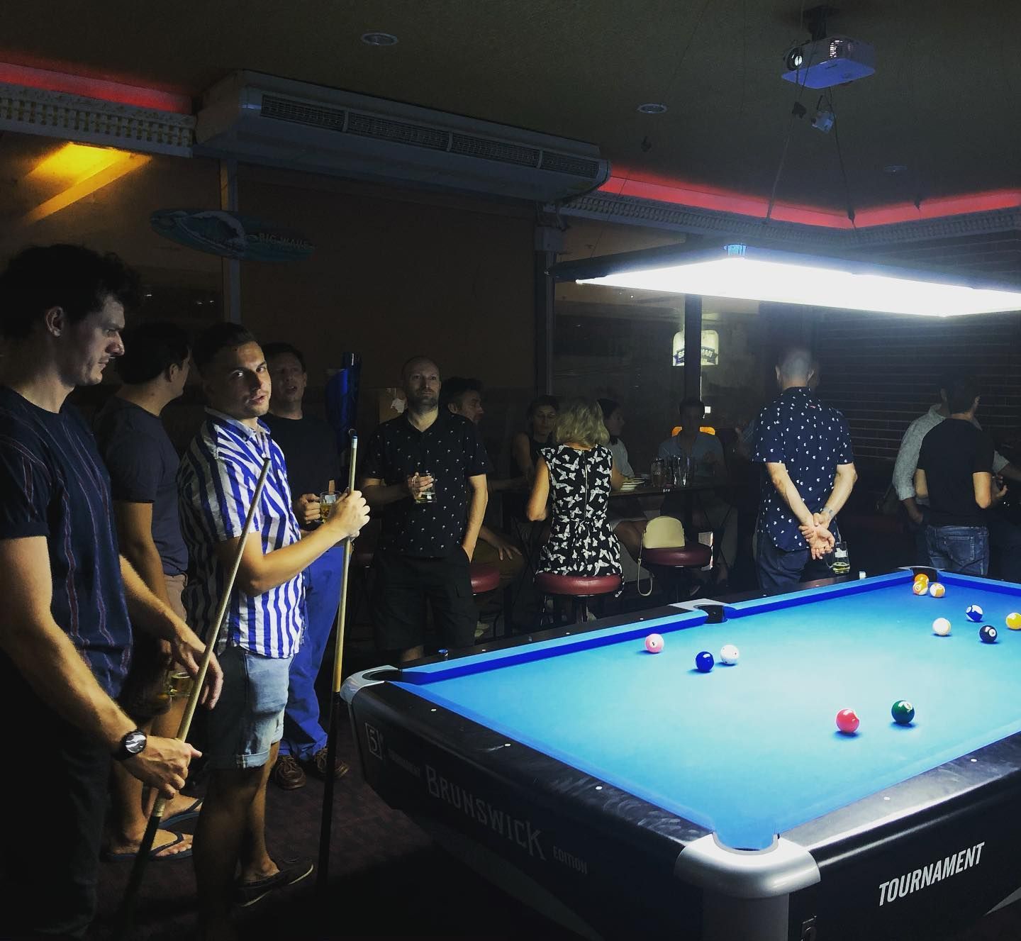 A group of people are standing around a pool table