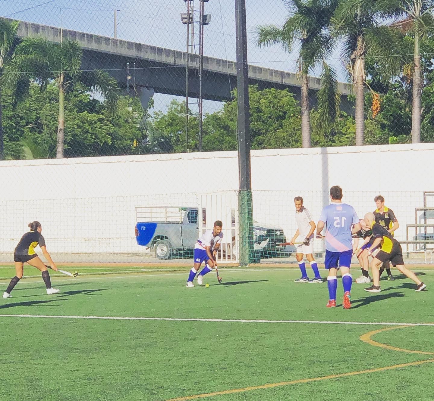 A group of people are playing soccer on a field with a bridge in the background