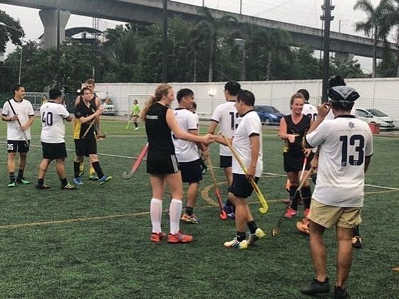 A group of people are playing field hockey on a field.
