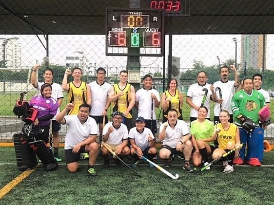 A group of people are posing for a picture in front of a scoreboard.