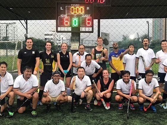 A group of people posing for a picture in front of a scoreboard