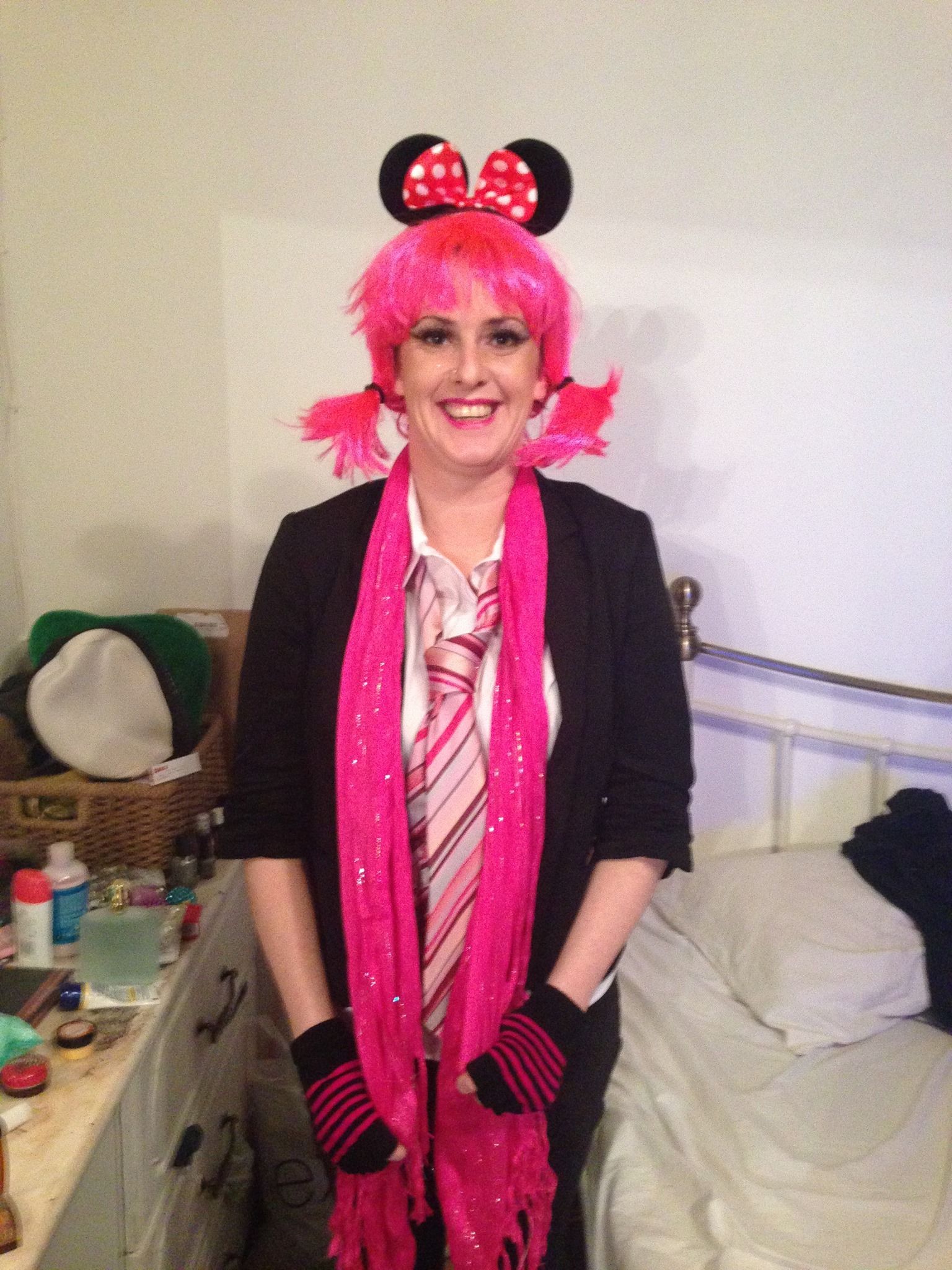 A woman wearing a pink wig and mickey mouse ears