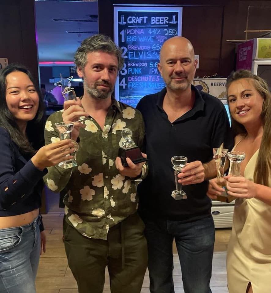 A group of people standing in front of a sign that says craft beer