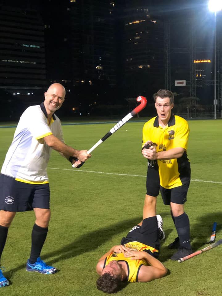 A group of men are playing field hockey on a field.