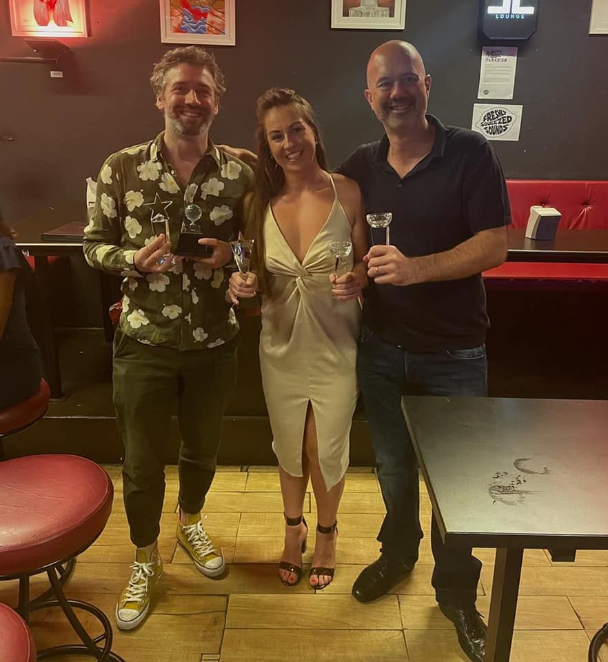 Three people standing next to each other holding wine glasses