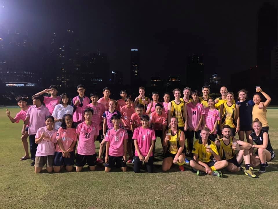 A group of people are posing for a picture on a field at night.