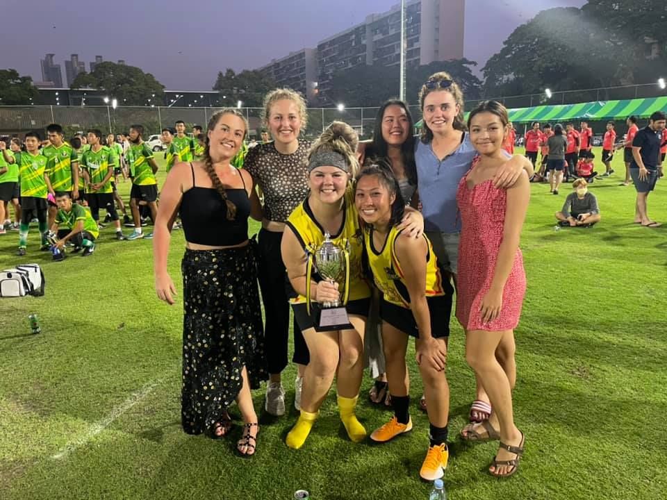 A group of women are posing for a picture on a soccer field.