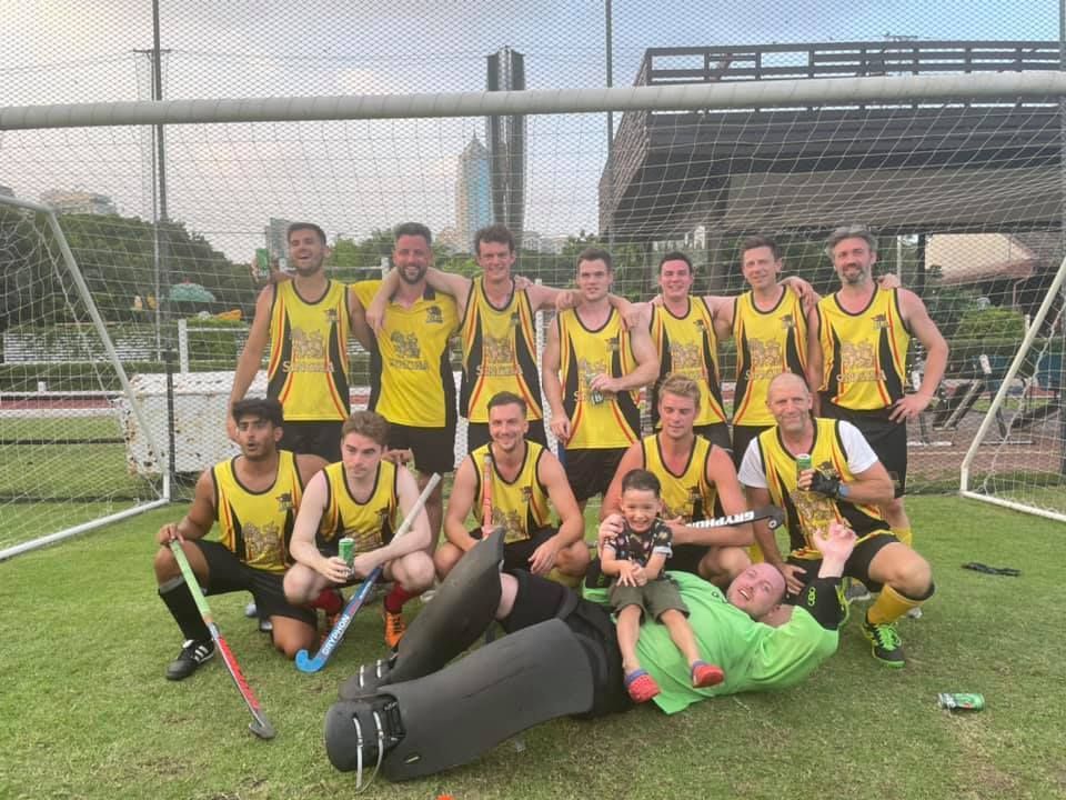 A group of men are posing for a picture on a field.
