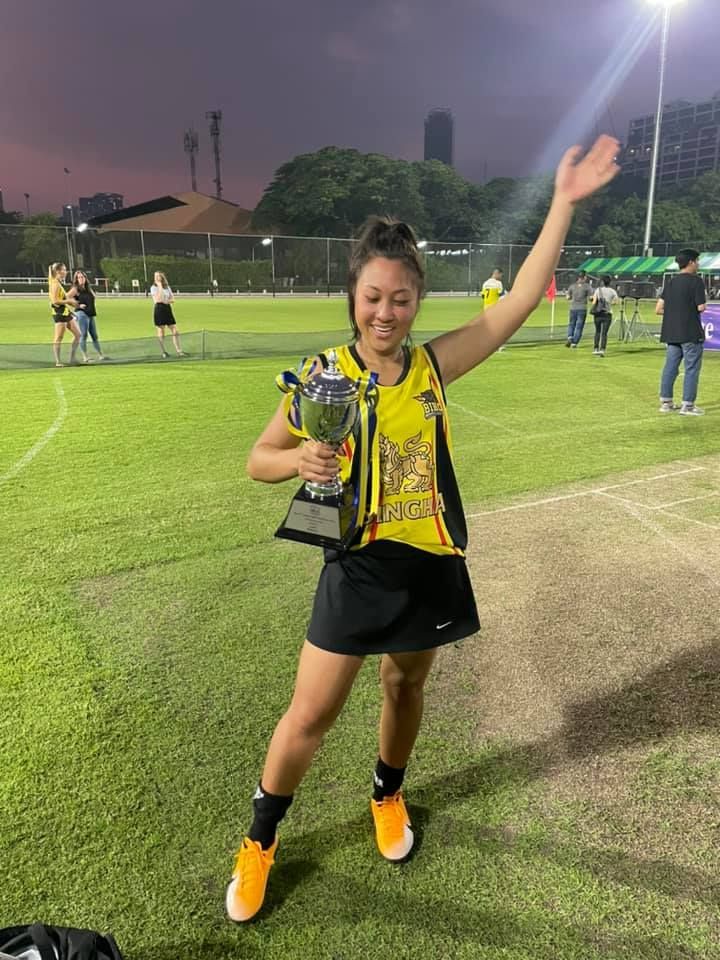 A woman is holding a trophy on a field.