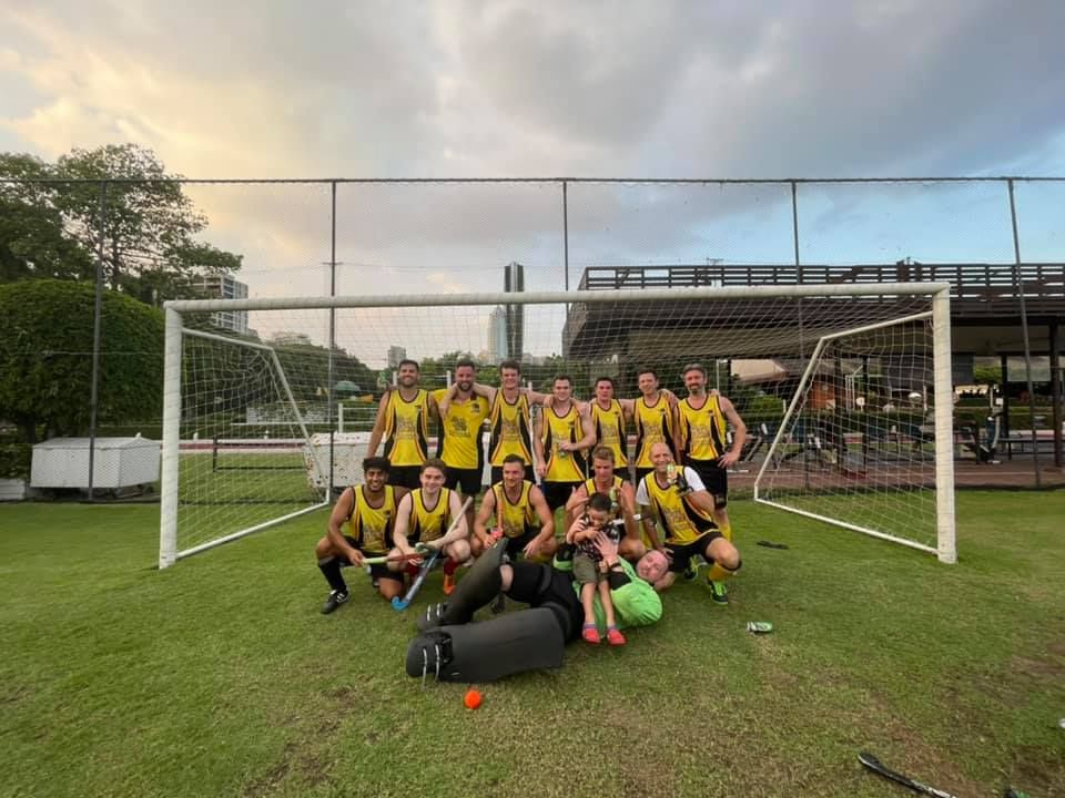 A group of people are posing for a picture in front of a soccer goal.