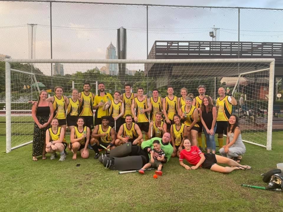 A group of people are posing for a picture on a soccer field.