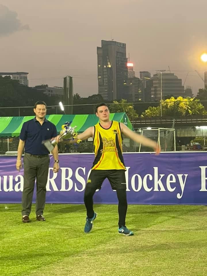 A man holding a trophy in front of a sign that says kbs