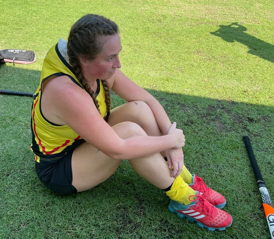 A woman is sitting on the grass with her legs crossed
