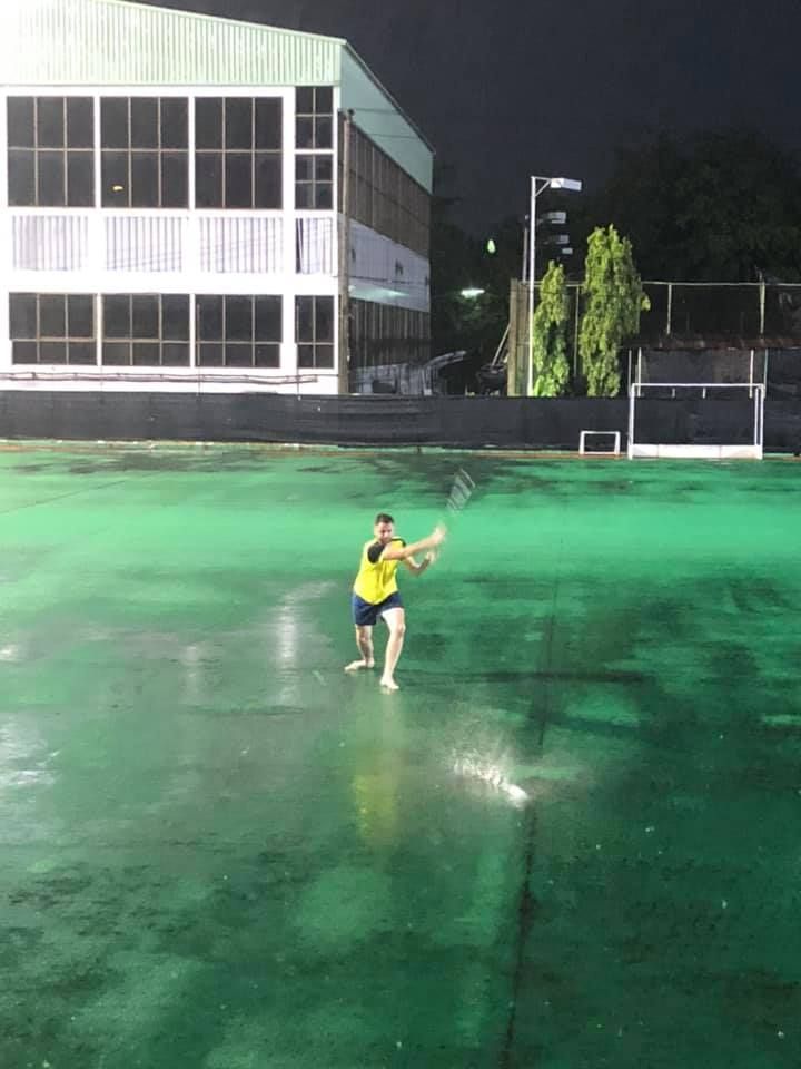 A man in a yellow shirt is playing tennis on a green court
