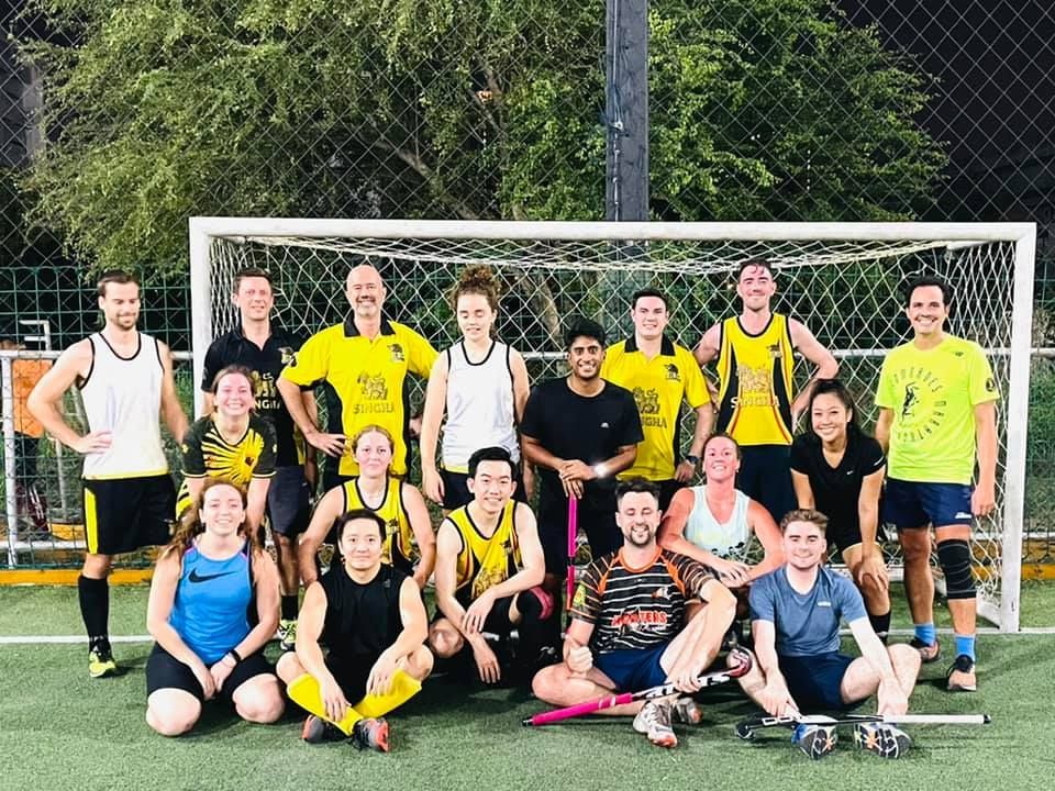 A group of people are posing for a picture on a soccer field.