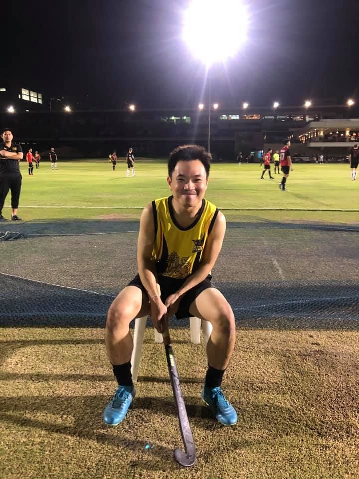 A young man is sitting on a chair with a hockey stick.