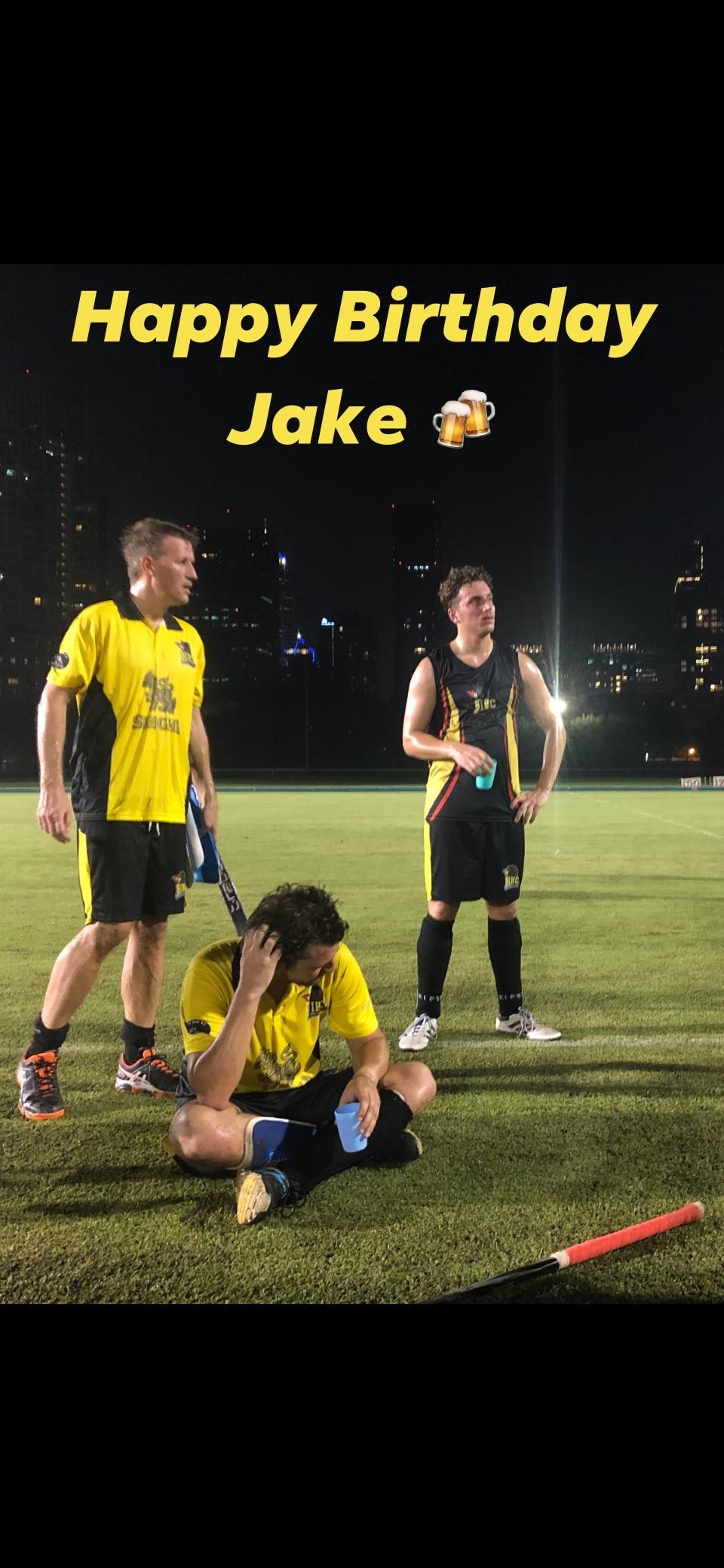 A group of soccer players are standing on a field at night.