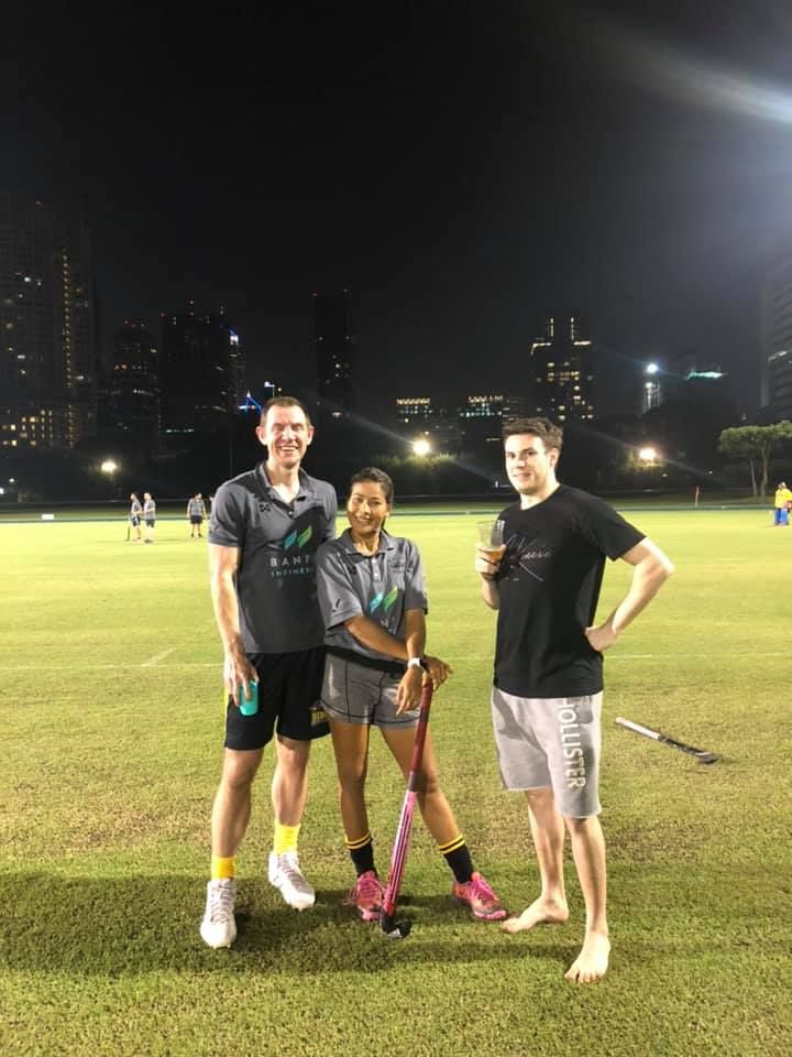 Three people are posing for a picture on a field at night.