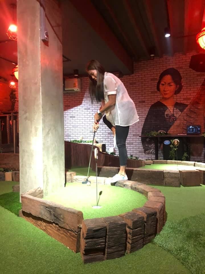 A woman is playing a game of mini golf in a room.