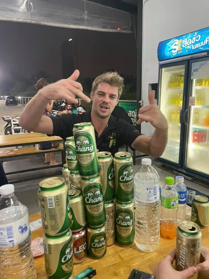 A man is standing in front of a stack of beer cans.