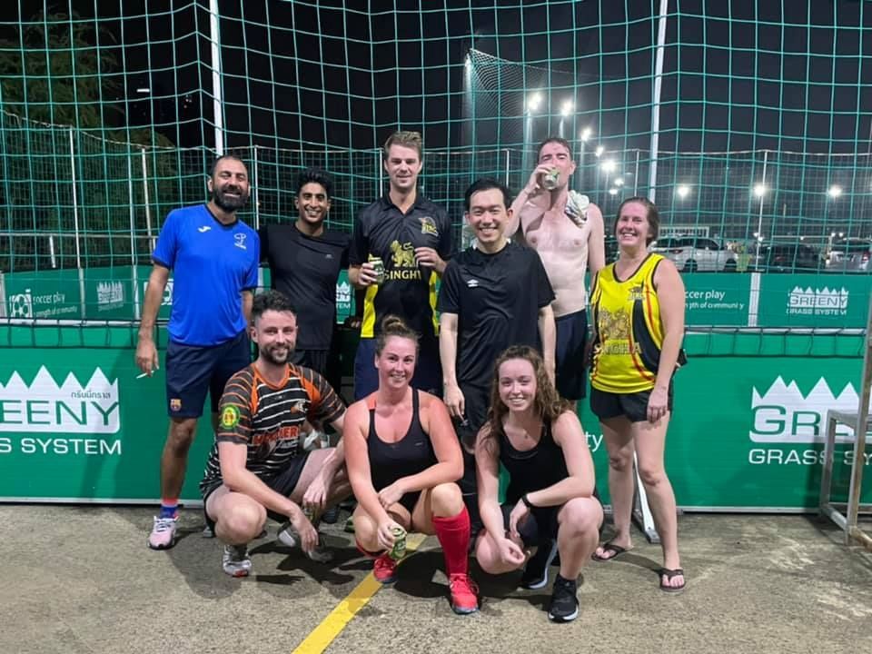 A group of people are posing for a picture on a soccer field.