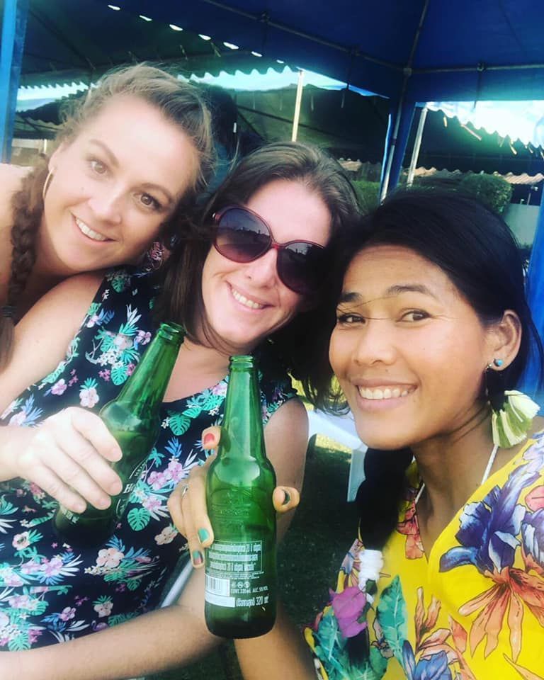 Three women are posing for a picture while holding beer bottles