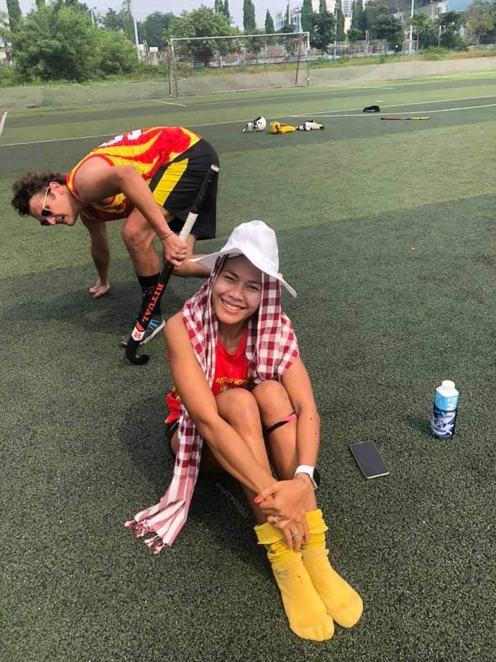 A man and a woman are sitting on the grass on a soccer field.