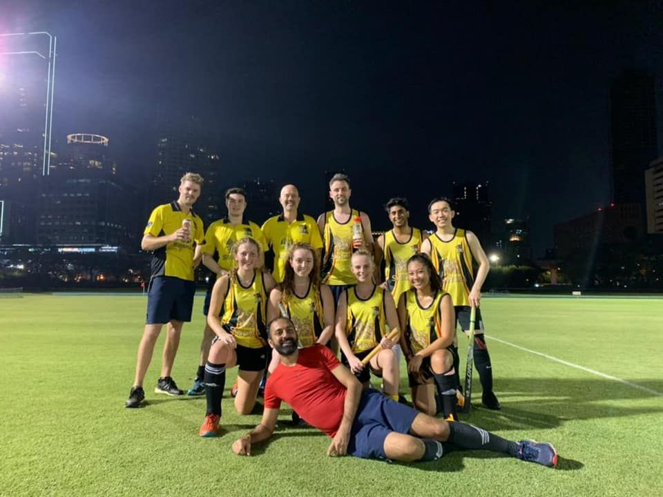 A group of soccer players are posing for a picture on a field at night.