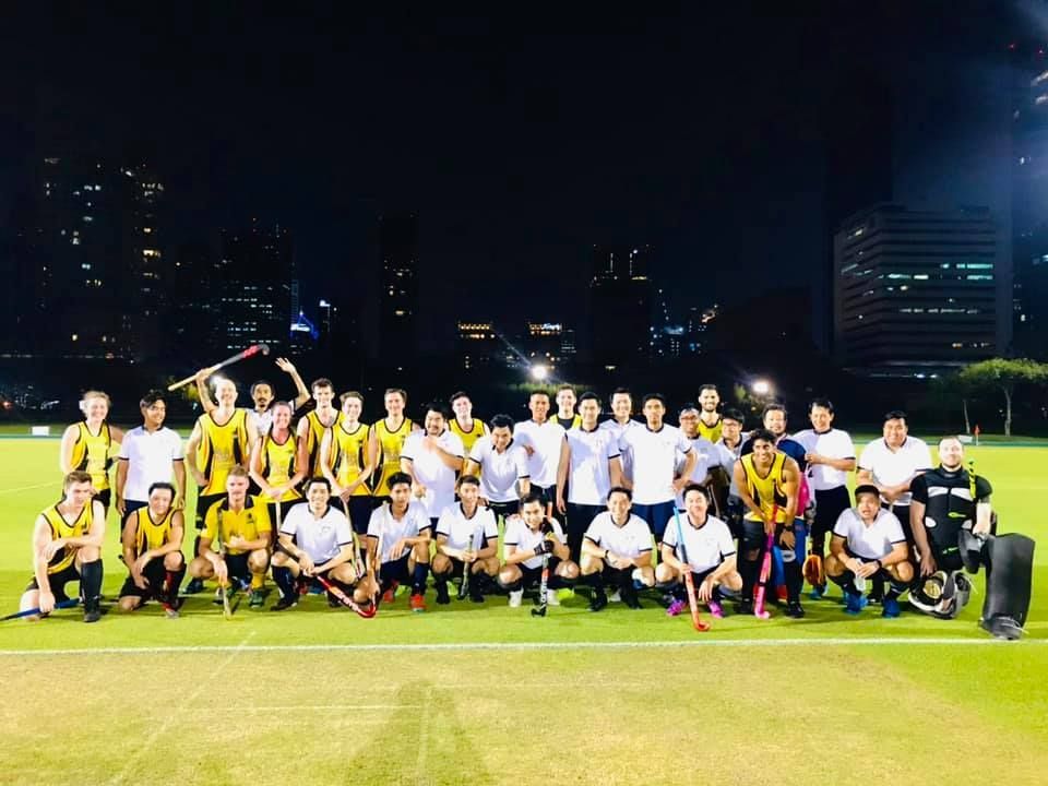 A group of people are posing for a picture on a field at night.