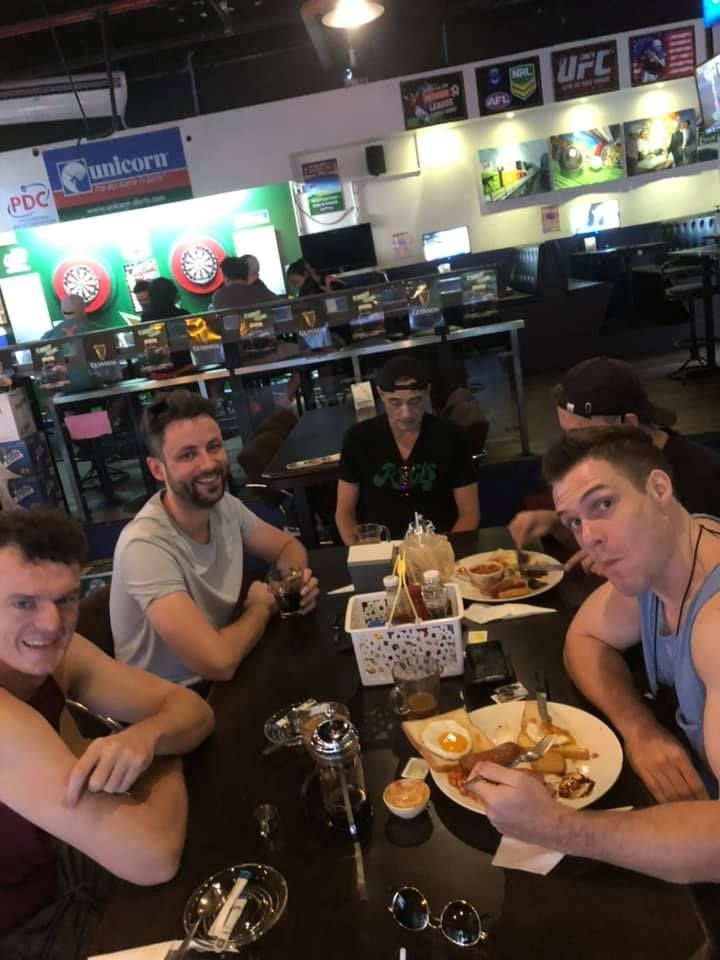 A group of men are sitting at a table with plates of food