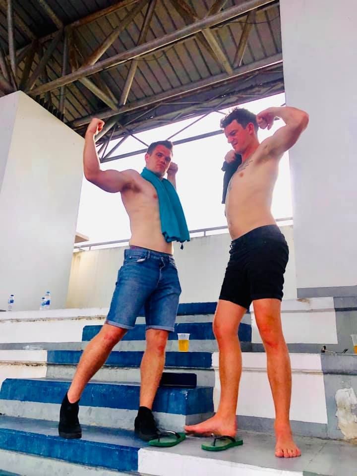 Two shirtless men are standing on a set of stairs