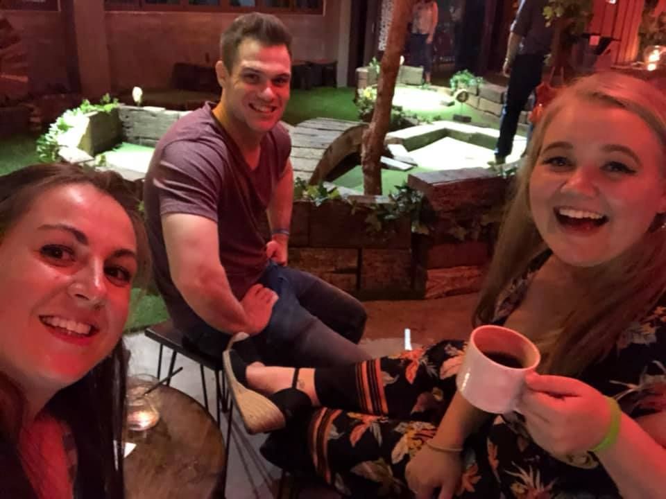A man and two women are sitting next to each other holding cups of coffee.