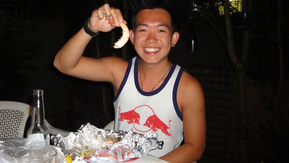 A man wearing a red bull tank top holds up a piece of food