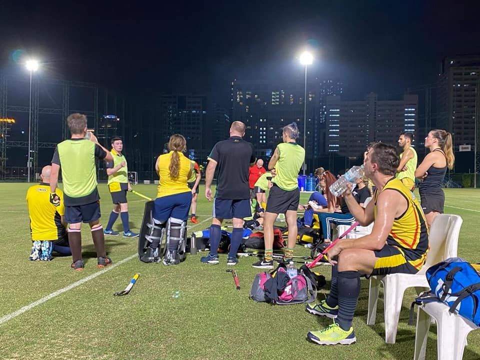 A group of people are standing on a soccer field at night.