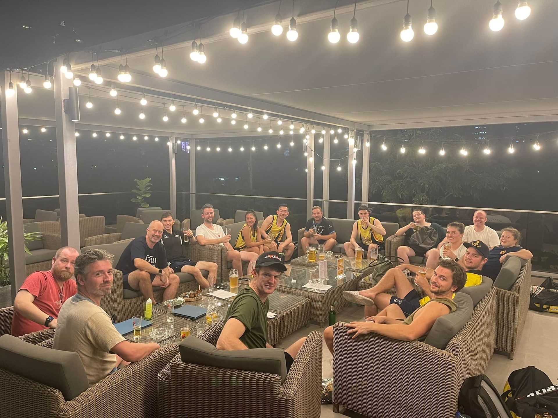 A group of people are sitting around a table on a patio at night.