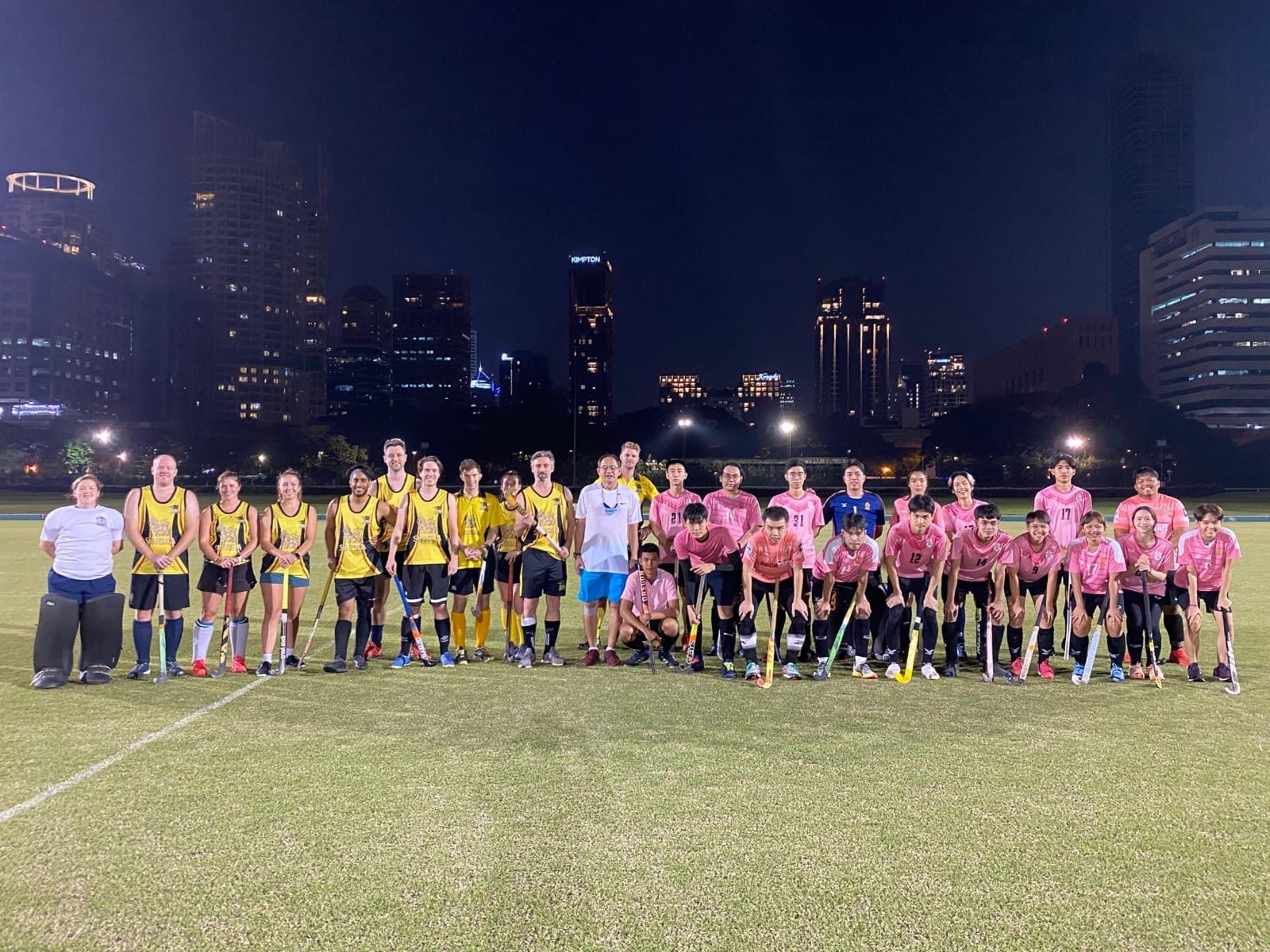 A group of soccer players are posing for a picture on a field at night.